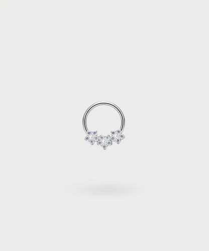 "Piercing Ring Olaya in titanium, zilverkleurig, met drie delicate bloemen ingelegd met zirkonen."